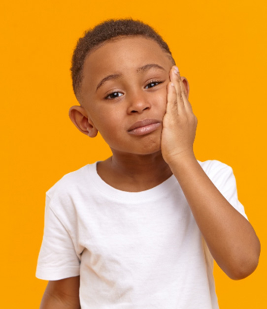 Little boy looking sad holding hand to cheek with goldenrod background