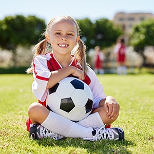 Child smiles while sitting on soccer field