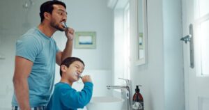 Dad and son brushing their teeth in bathroom